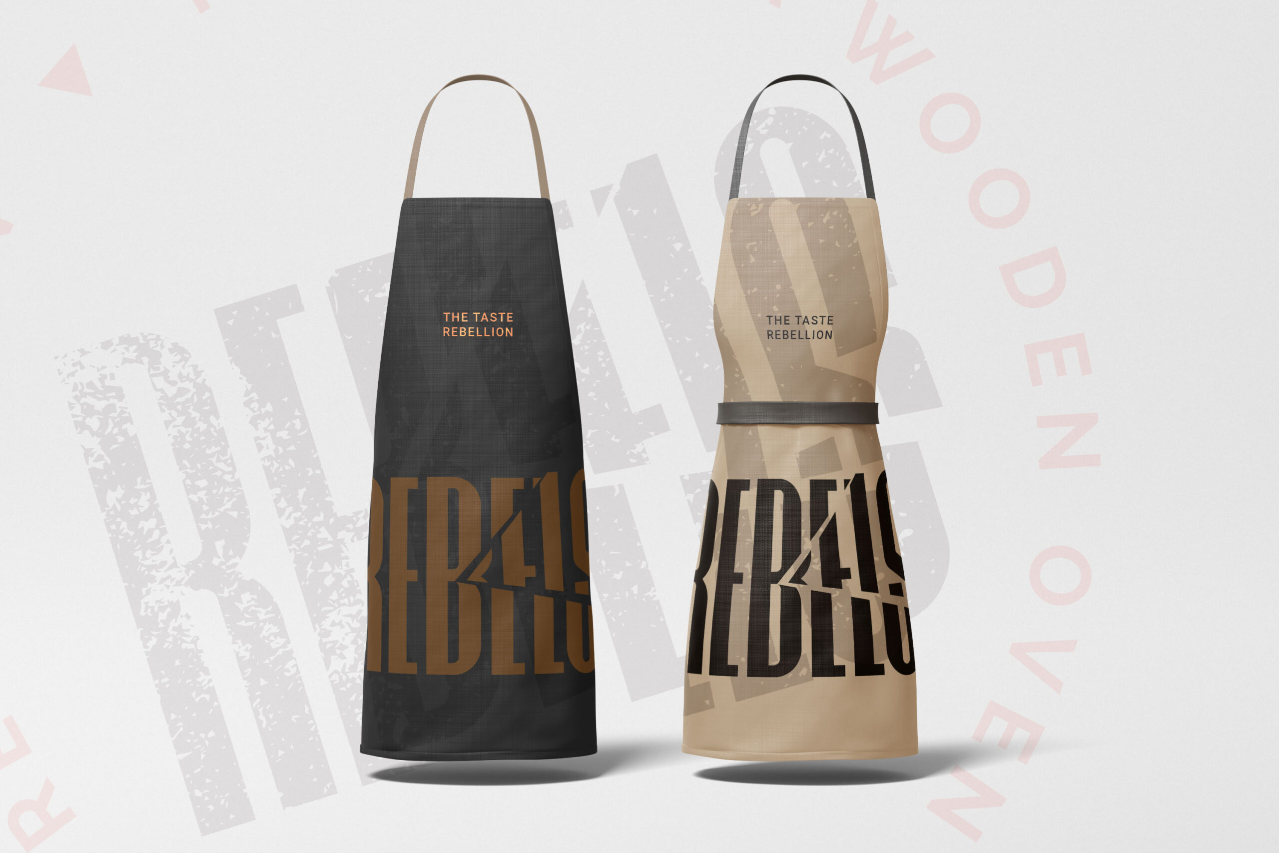 Dark grey and tan staff aprons featuring a bold cut-typography logo for Rebels Pizza. Brand identity design by MVOG Studio.